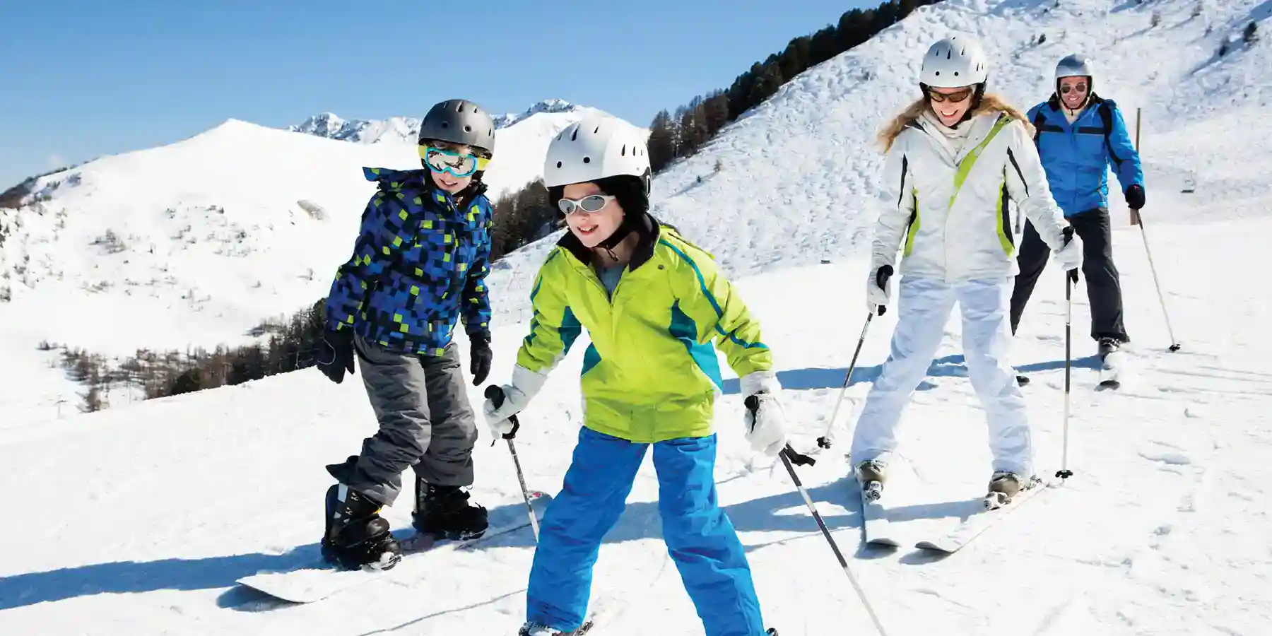 A family of four (parents skiing, son snowboarding, and daughter skiing) enjoys a sunny day on the slopes, combining a family ski vacation with a CME/CE conference.