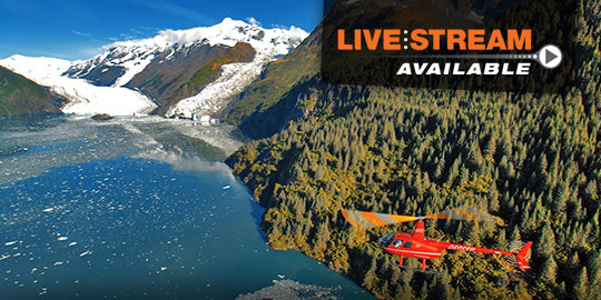 Red helicopter flying over glacier-fed waters near Alyeska Resort in Alaska, promoting the 2026 Anchorage CME conference with livestream option