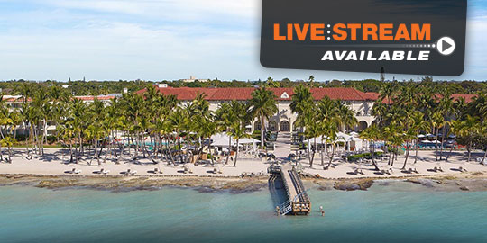 Aerial view of the Casa Marina Key West beachfront resort, showing the sandy beach, lounge chairs, palm trees, and the long pier extending into turquoise water.
